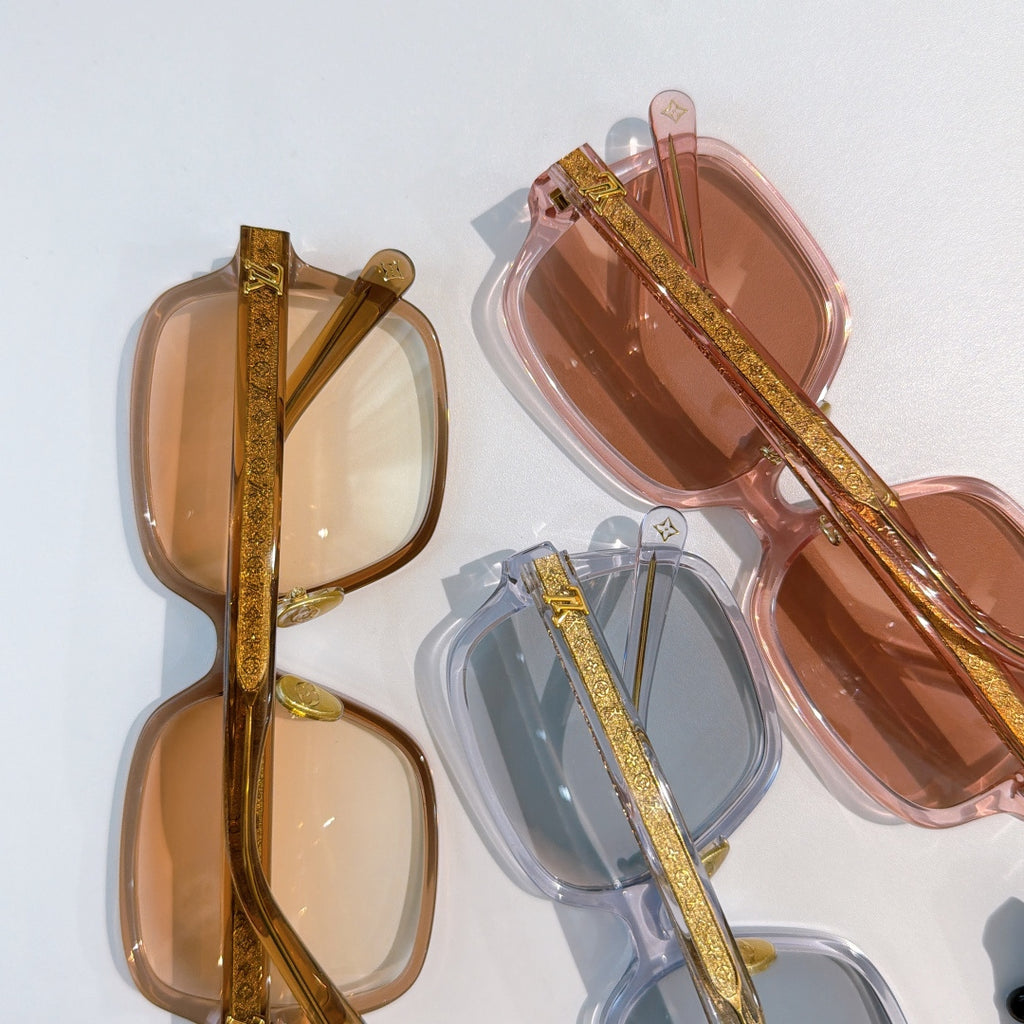 Assorted sunglasses frames with gold temple details in clear, blue, and brown