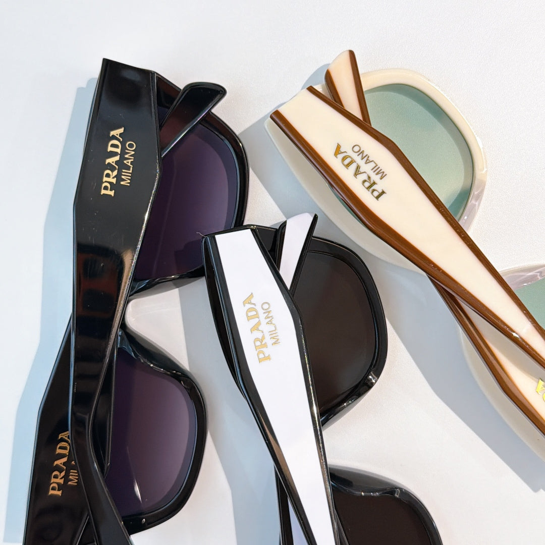 Prada sunglasses assortment with black and tan frames and tinted lenses, stacked pair view
