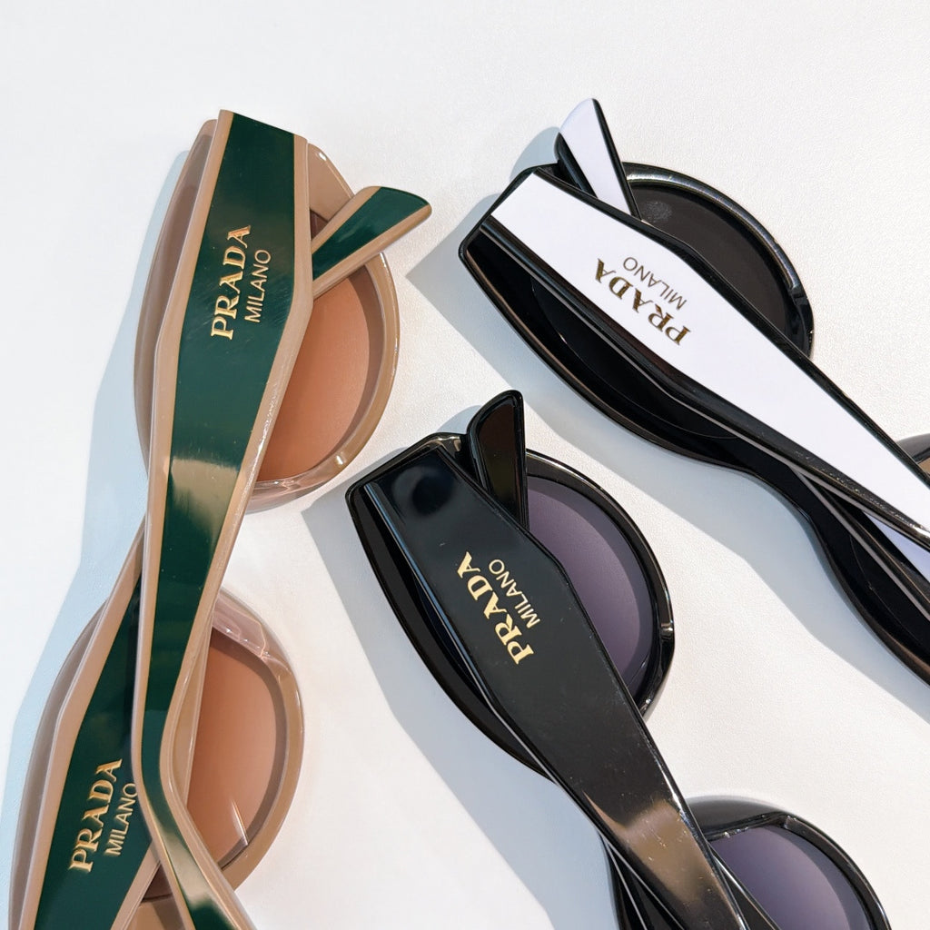 Prada sunglasses with brown and black tinted lenses, logo temples visible.