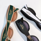Prada sunglasses with brown and black tinted lenses, logo temples visible.