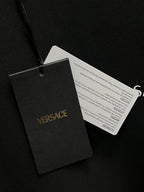 Versace hang tags attached to a dark gray crewneck sweatshirt