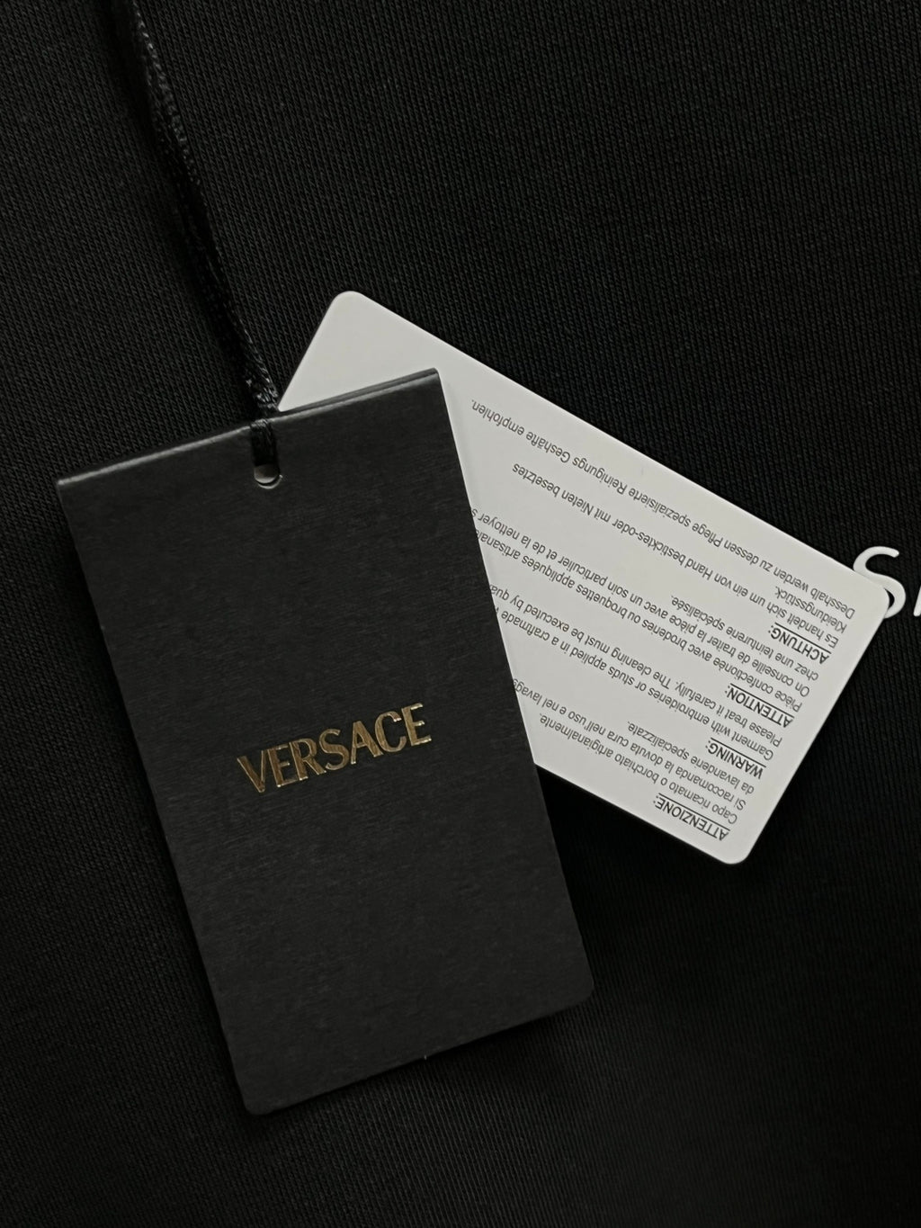 Black hang tag with Versace logo and product label on string