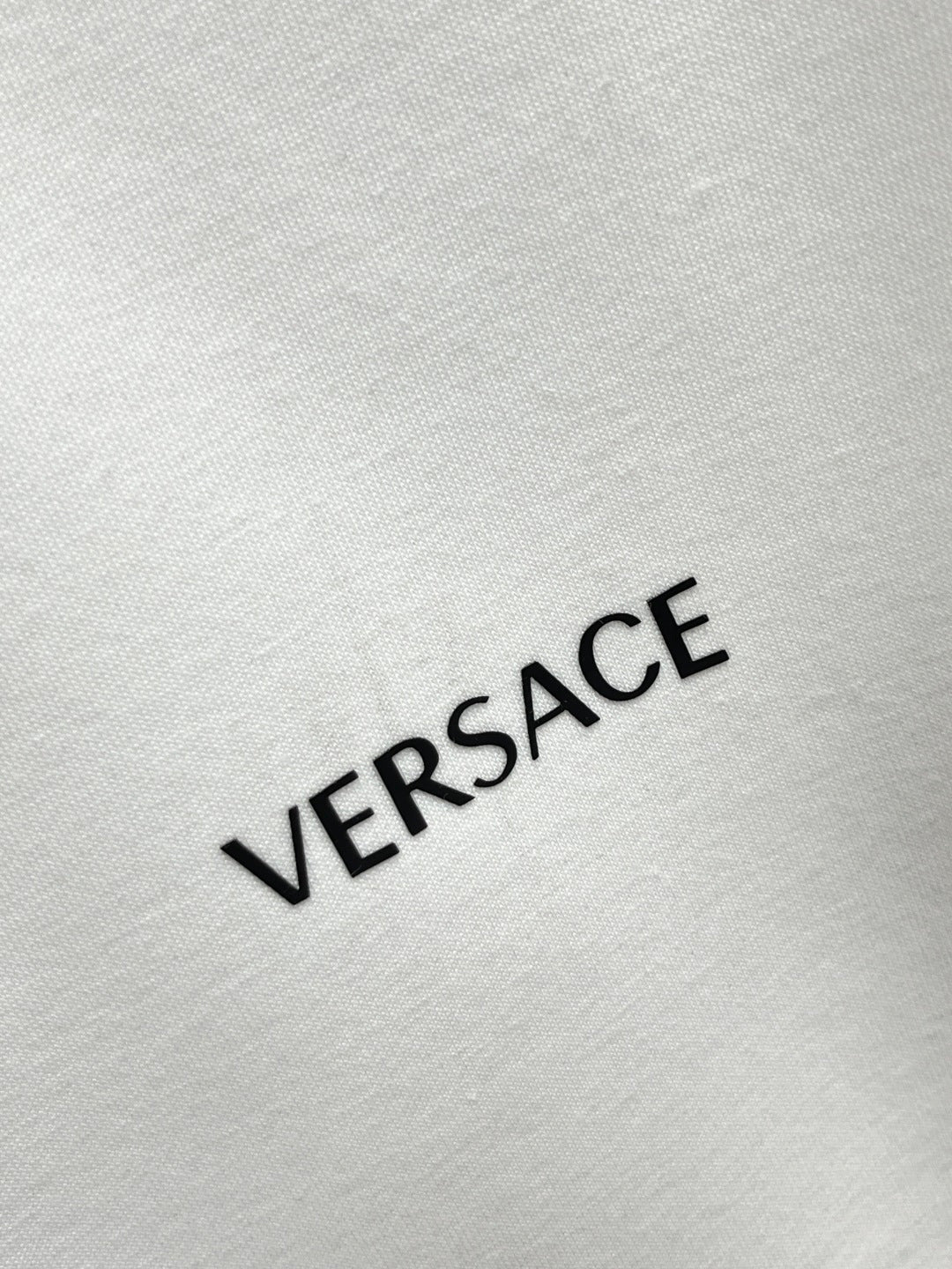 VERSACE logo print on white sweatshirt fabric.