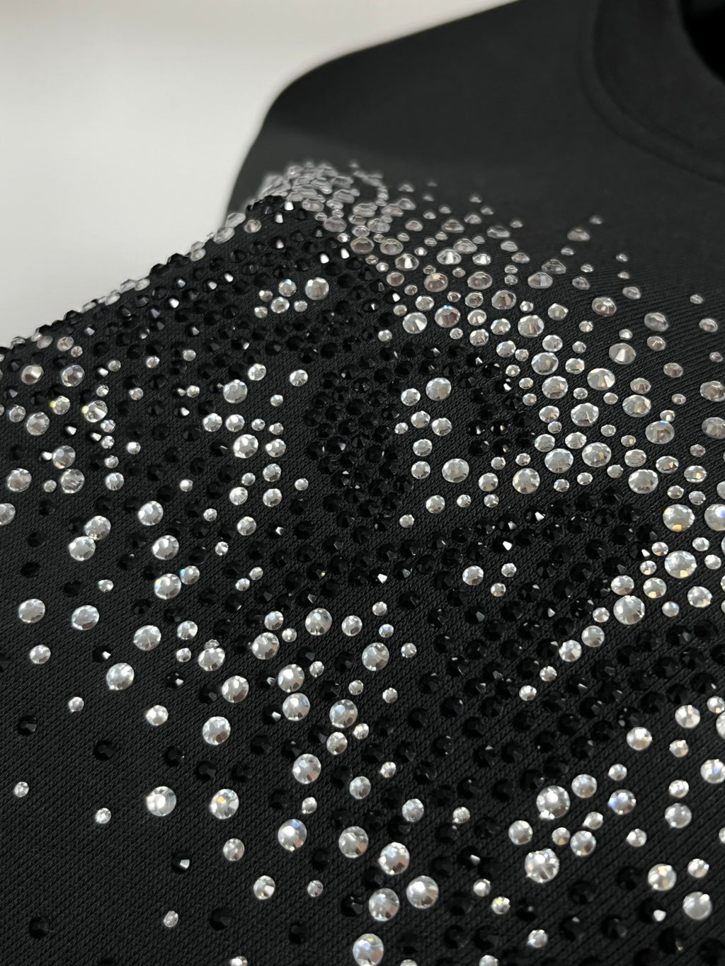 Black sweatshirt with dense rhinestone stud pattern across the front