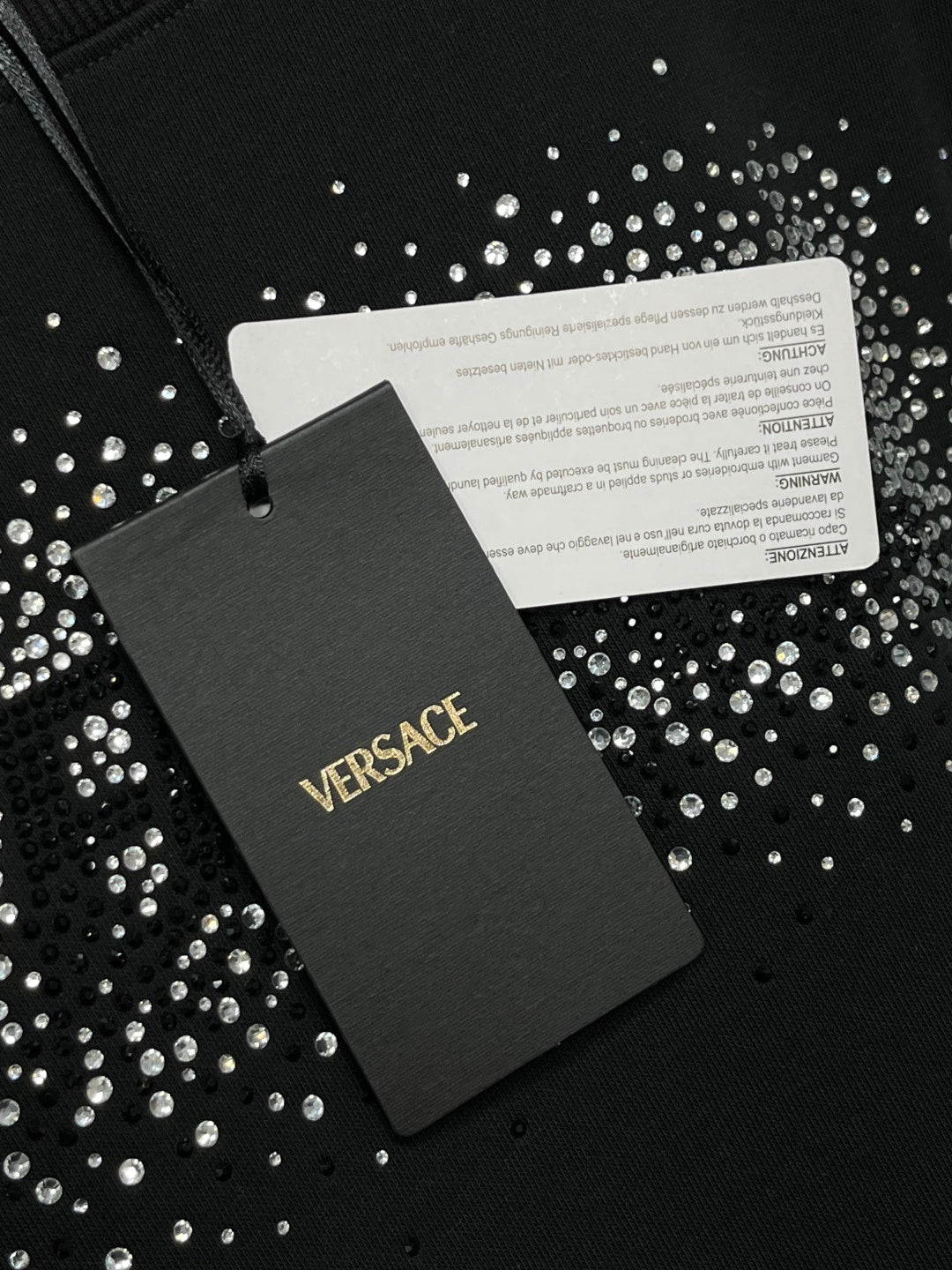 Black VERSACE sweatshirt with brand label tag on studded logo fabric