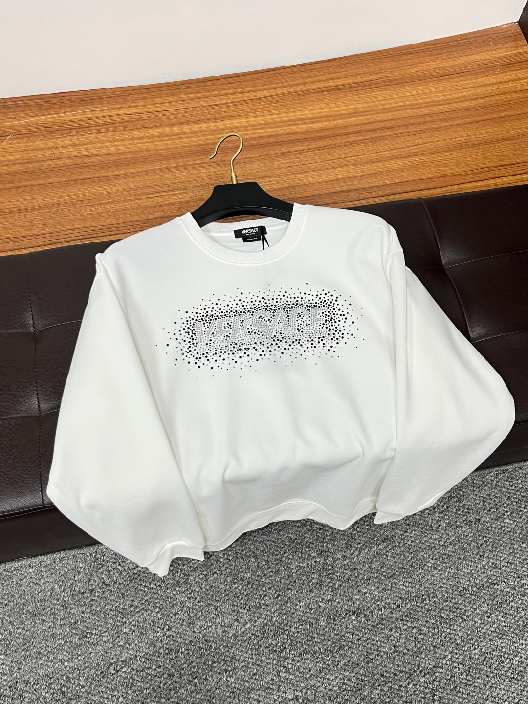 White crewneck sweatshirt with rhinestone logo on chest, folded on seat