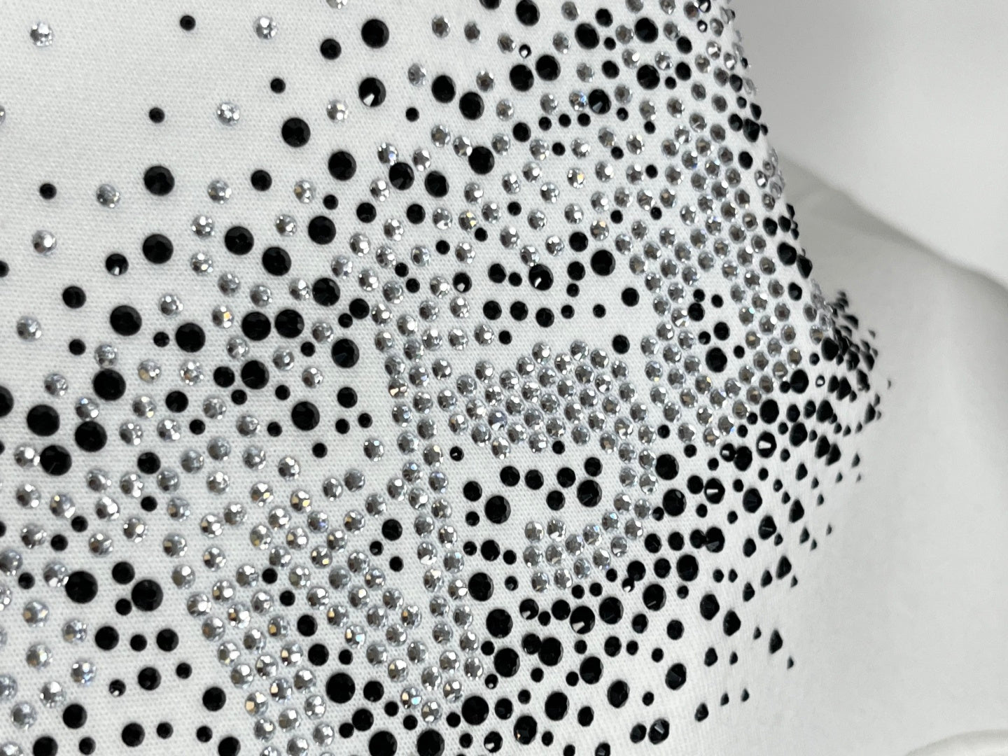 Rhinestone-studded logo pattern on white sweatshirt
