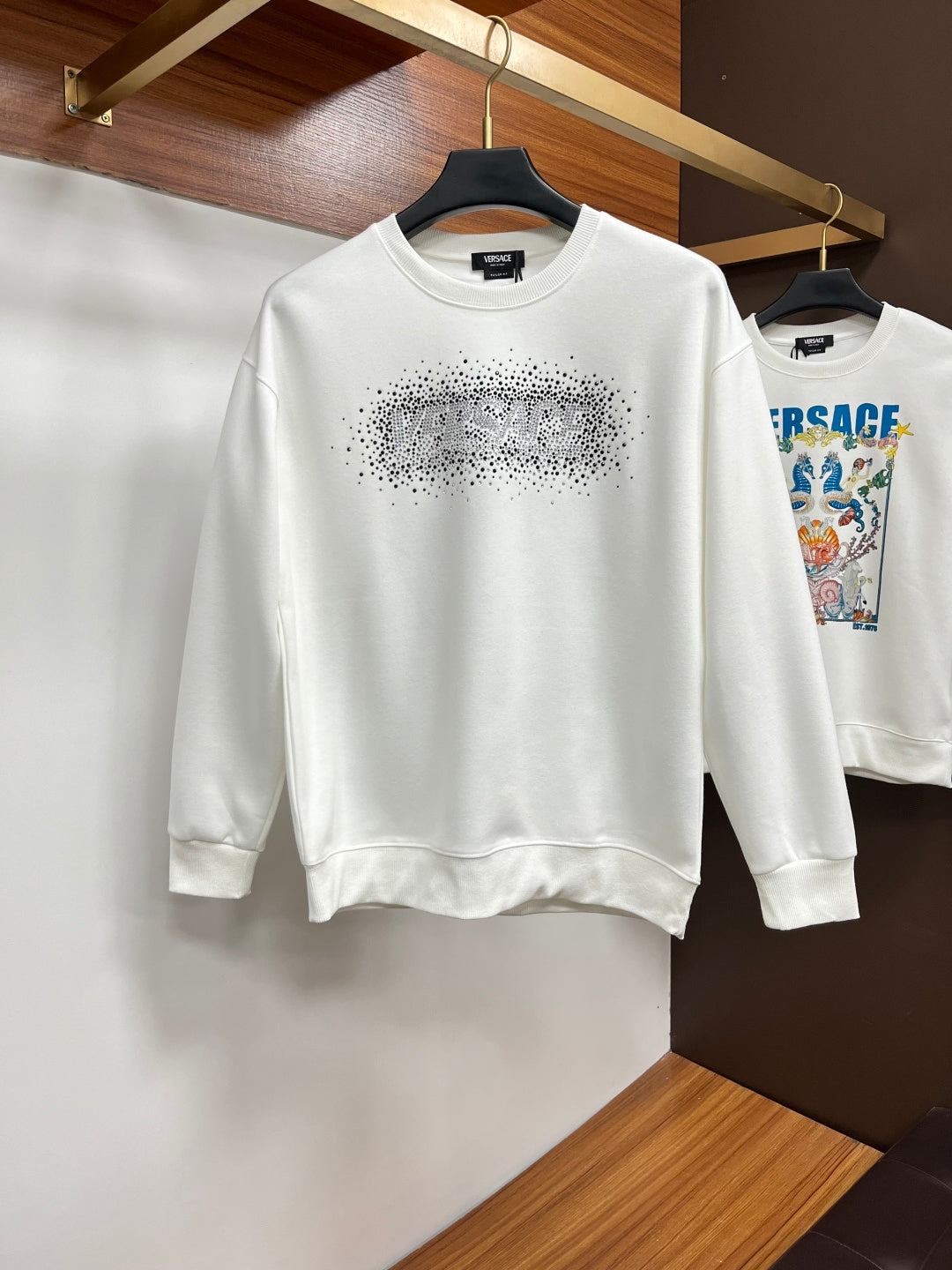 White crewneck sweatshirt with rhinestone logo across chest