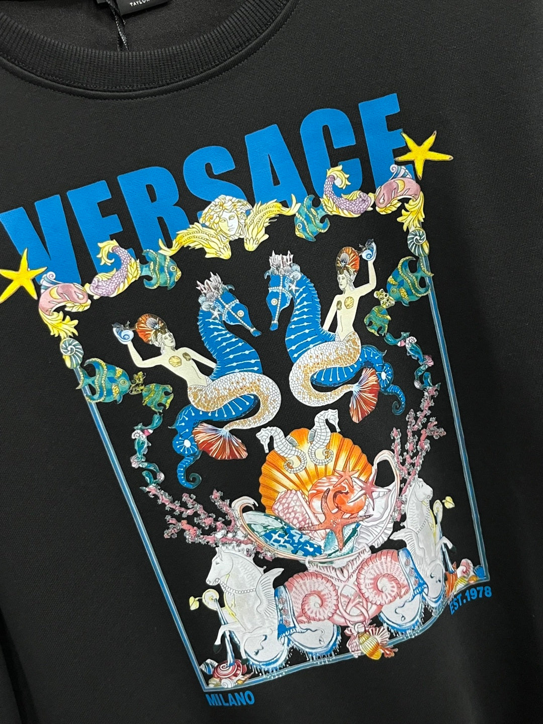 Black crewneck sweatshirt close-up of Versace graphic illustration