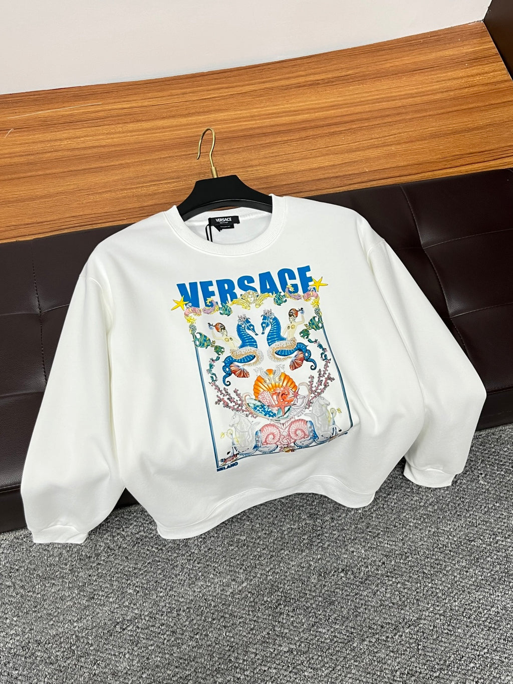 White crewneck sweatshirt with colorful crest graphic and blue VERSACE logo front