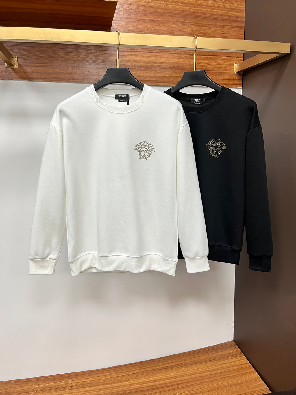 White and black crewneck sweatshirts with gold-tone studded lion head emblems