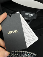 Black sweatshirt with hanging VERSACE brand label and care tag near collar
