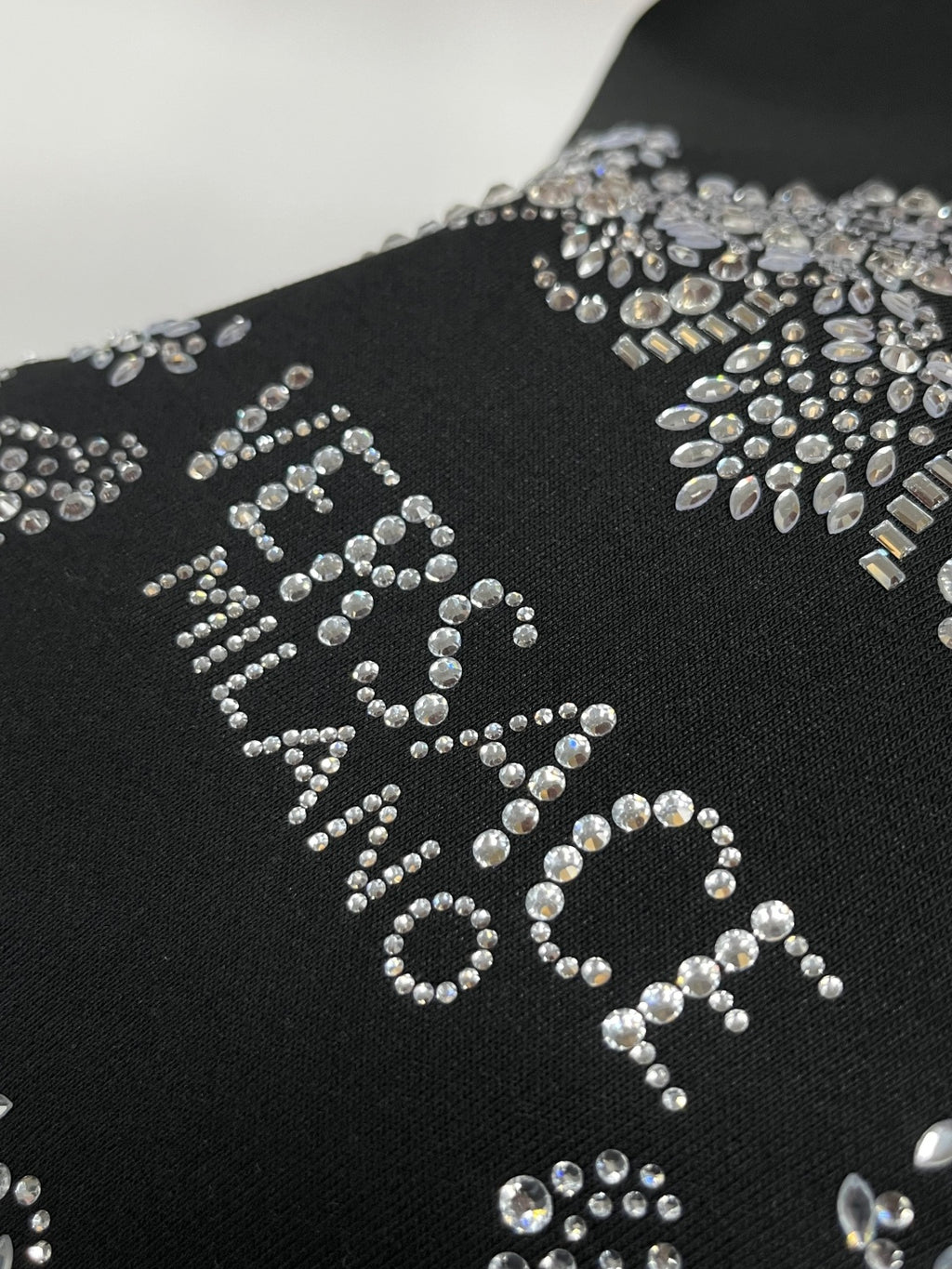 Black sweatshirt with large rhinestone logo design across the front