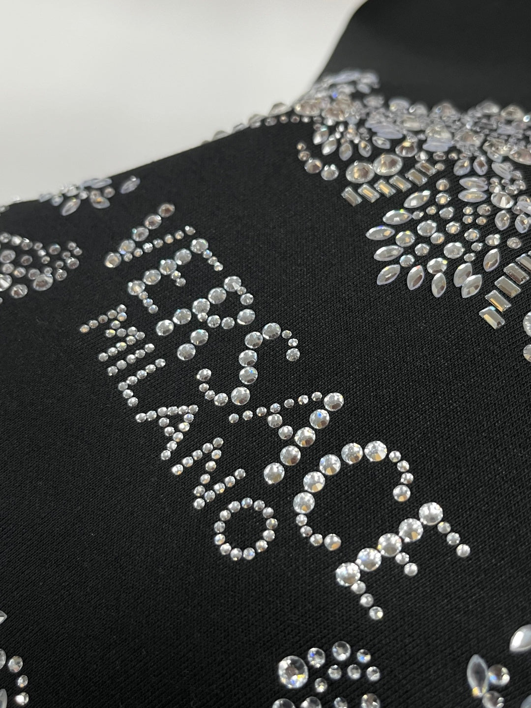 Black sweatshirt with large rhinestone logo design across the front