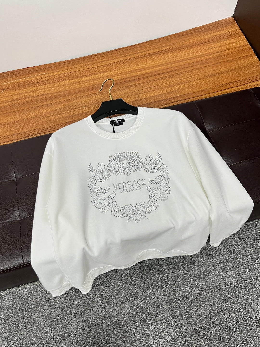 White crewneck sweatshirt with rhinestone crest logo on chest