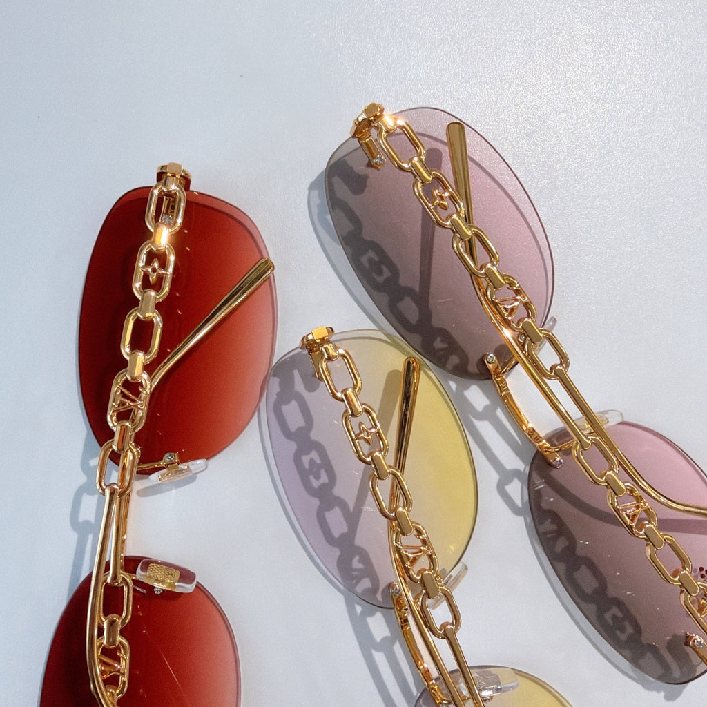 Louis Vuitton sunglasses close-up with gold chain frames and red, yellow, and pink lenses