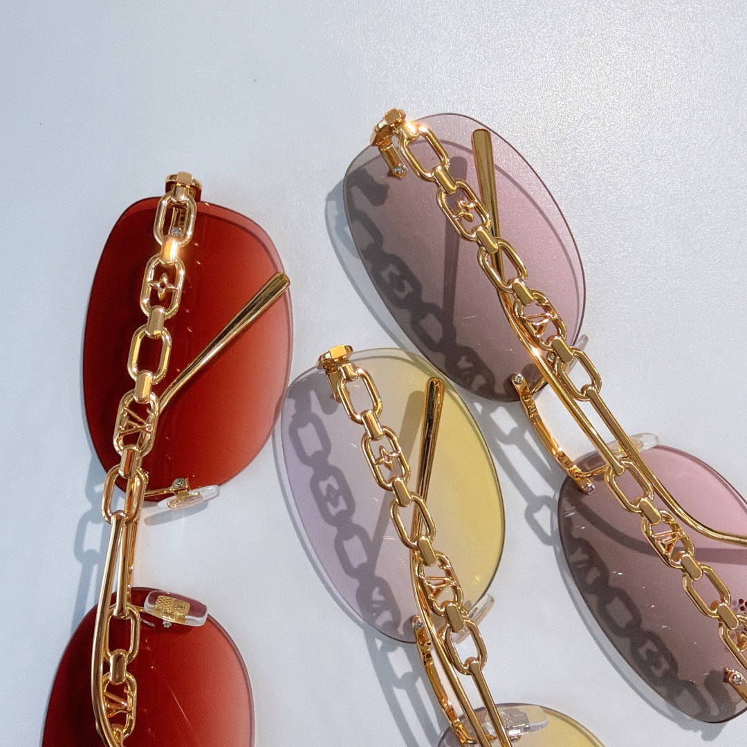 Louis Vuitton sunglasses close-up with gold chain frames and red, yellow, and pink lenses