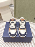 Navy and white low-top sneakers with tan trim, white laces, and Dior “D” logo tabs