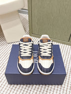 Navy and white low-top sneakers with tan trim, white laces, and Dior “D” logo tabs