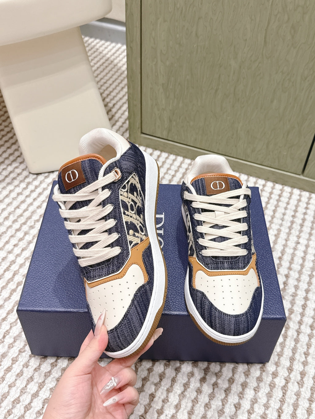 Navy and cream low-top sneakers on a box, tan trim, white laces, Dior logo tab