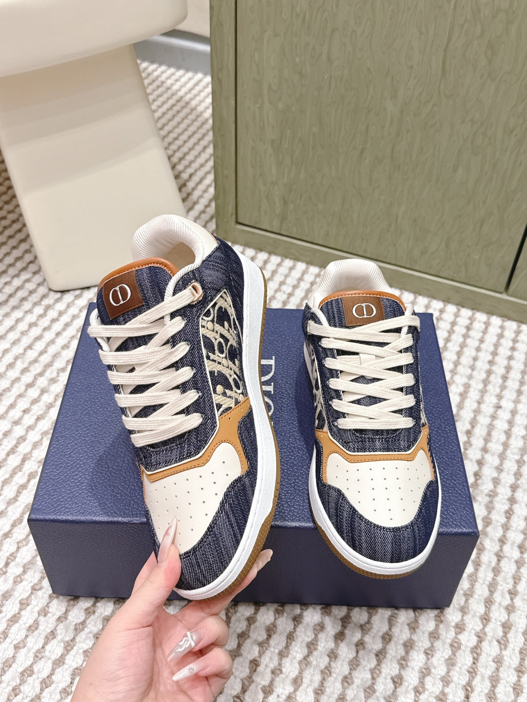 Navy and cream low-top sneakers on a box, tan trim, white laces, Dior logo tab