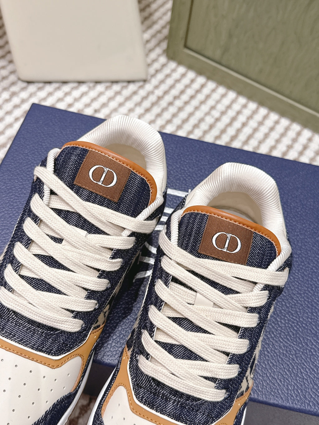 Navy-and-cream low-top sneakers with white laces and tan “D” logo on tongue