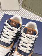 Navy-and-cream low-top sneakers with white laces and tan “D” logo on tongue