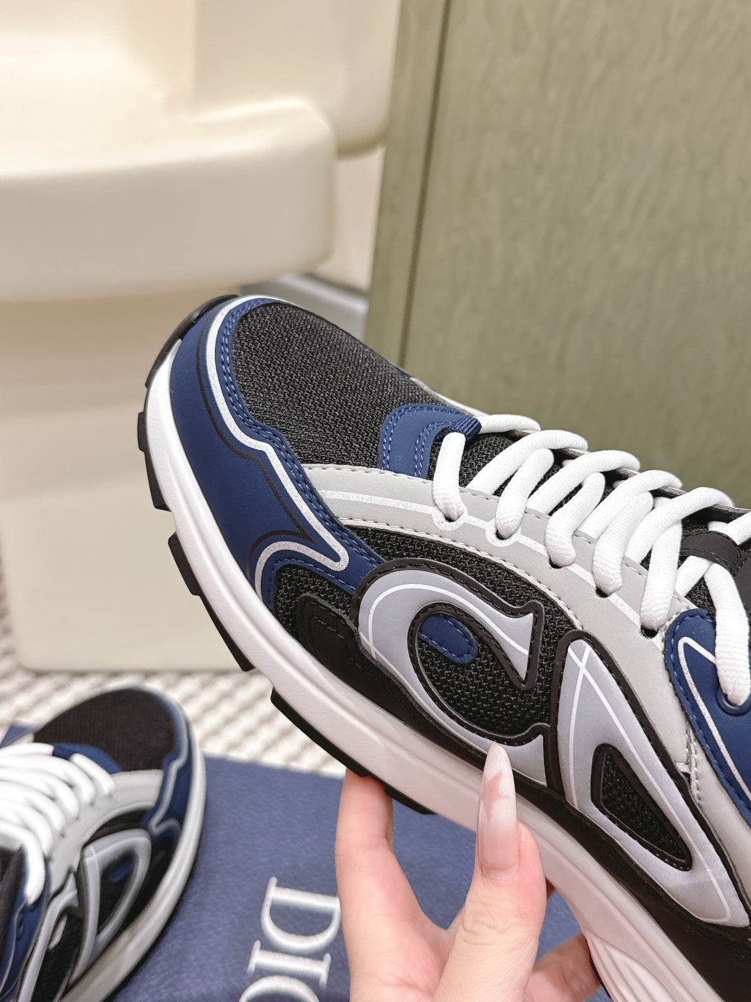 Dior unisex sneaker close-up, navy and black upper with white laces and oval logo