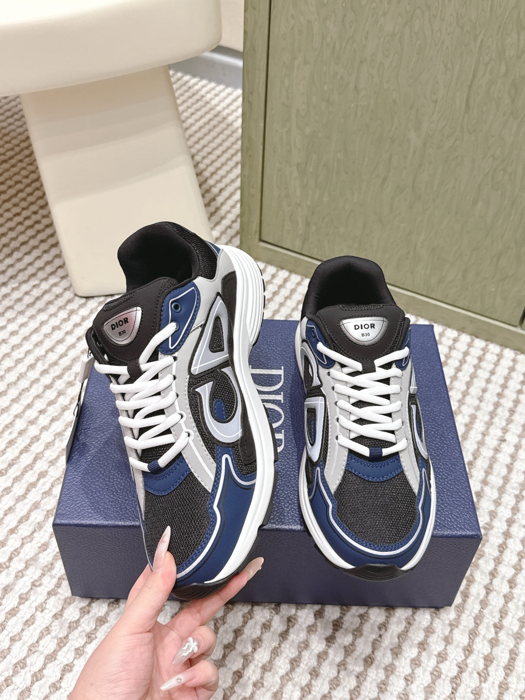 Dior unisex sneakers held in hand, navy and black with white laces and logo patch
