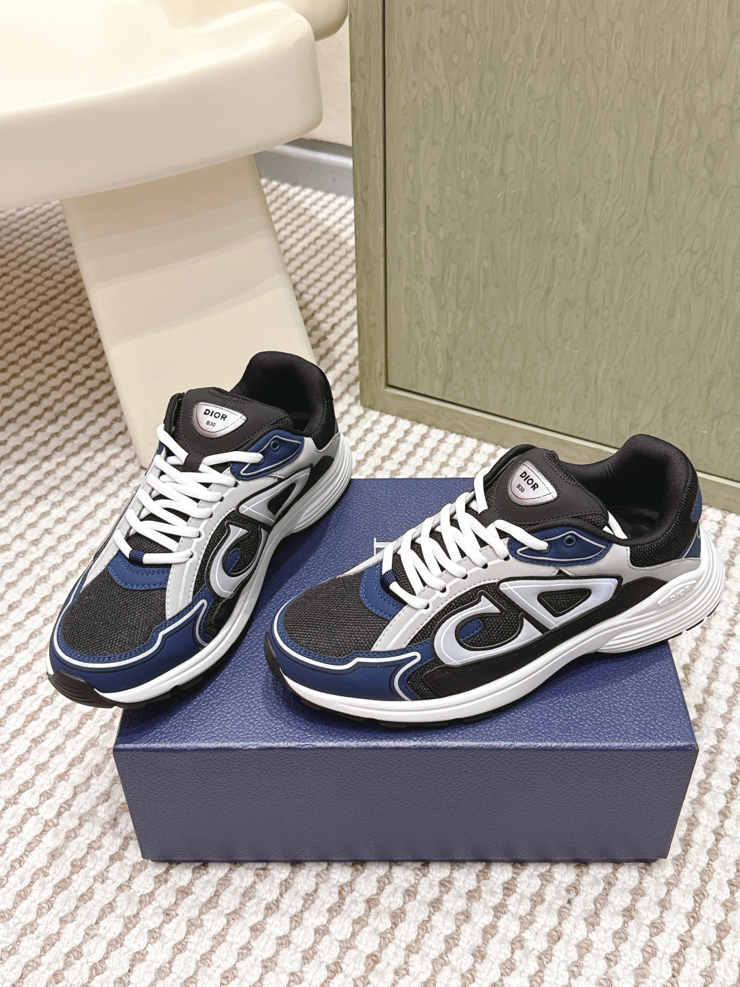Dior unisex sneakers on a box, navy and black uppers with white lace trim