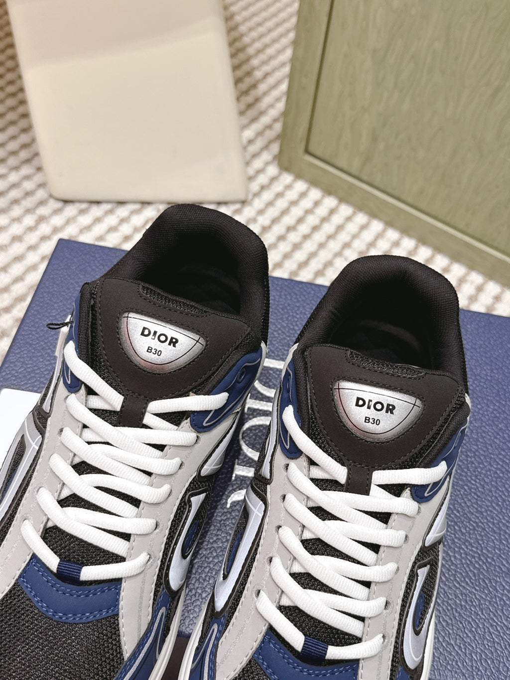Dior unisex sneakers close-up on box, black uppers with navy accents and white laces