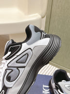 White Dior sneakers with gray mesh panels and ribbed rubber sole.
