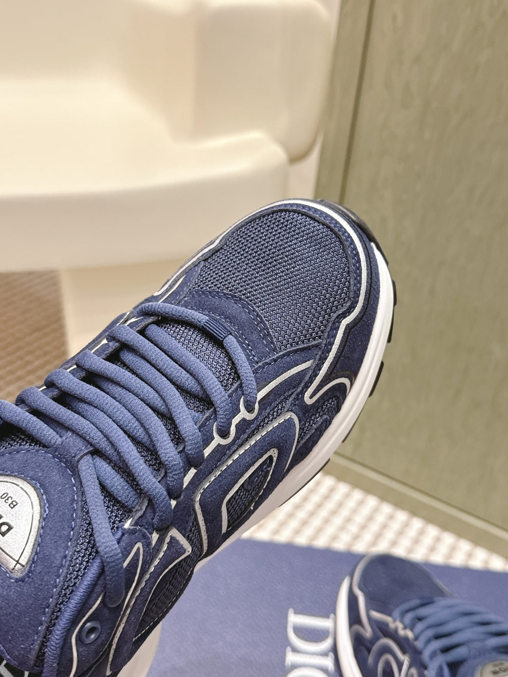 Navy Dior unisex sneaker close-up of laces and side logo with white edge trim