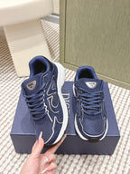 Navy Dior unisex sneakers held in hand; lace-up upper with white trim and logo