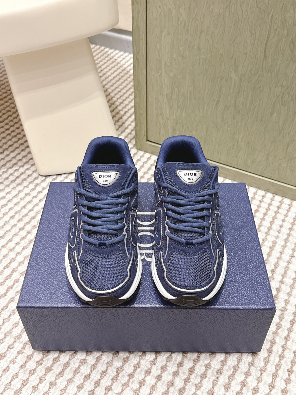 Navy Dior unisex sneakers with white midsoles and lace-up front, on blue box
