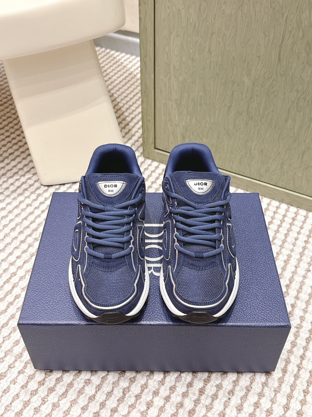 Navy Dior unisex sneakers with white midsoles and lace-up front, on blue box