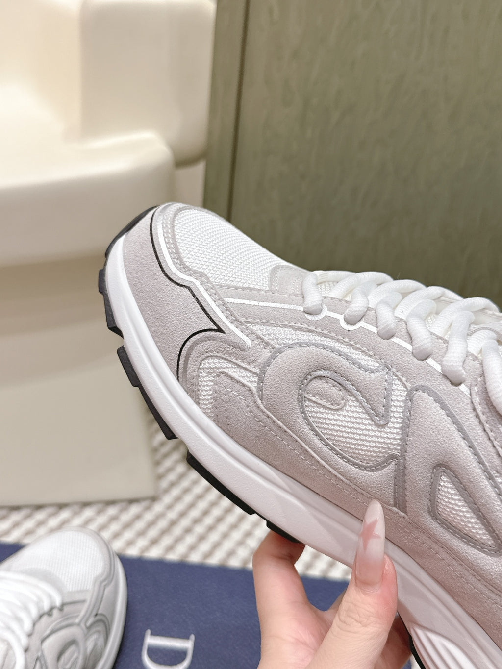 White and light gray Dior sneakers, side profile close-up with laces and overlay.