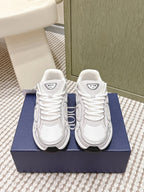 White Dior low-top sneakers with lace-up front and thick rubber sole on box.