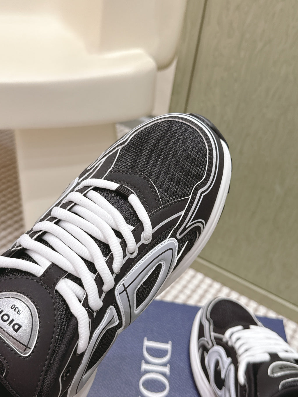 Black Dior unisex sneaker top view on blue box, white laces