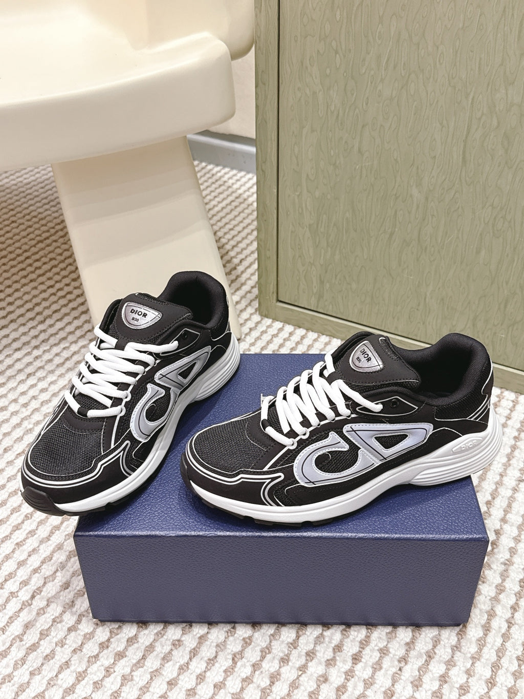 Black and white Dior unisex sneakers, side view on blue box