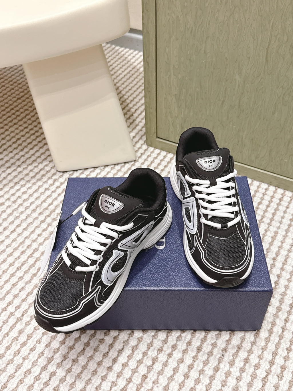 Black and white Dior unisex sneakers, three-quarter view on blue box