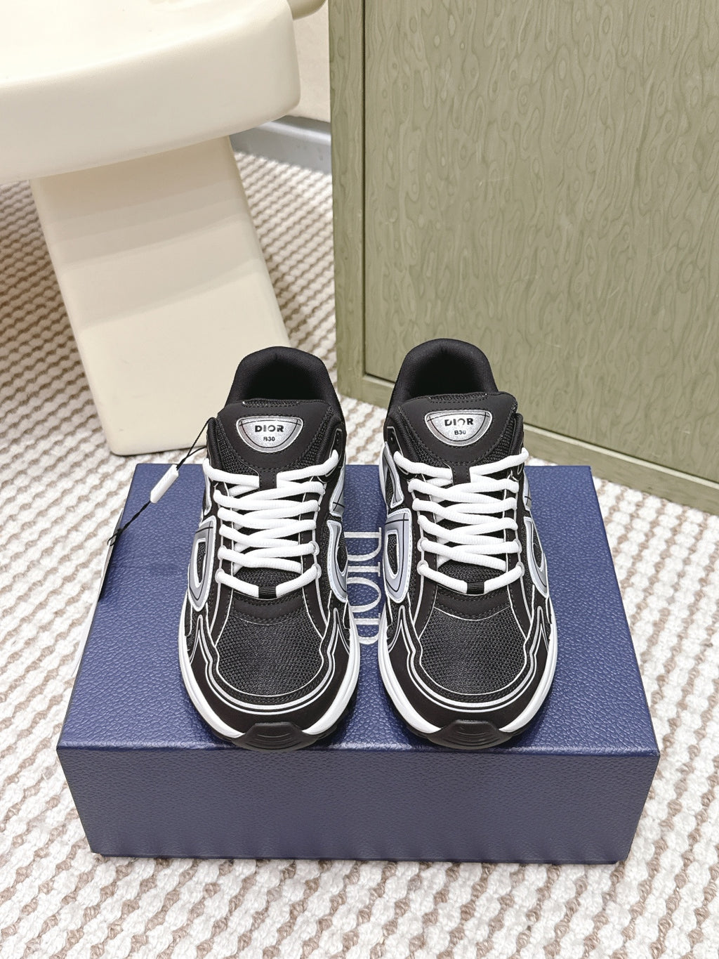 Black and white Dior unisex lace-up sneakers on blue box, front view