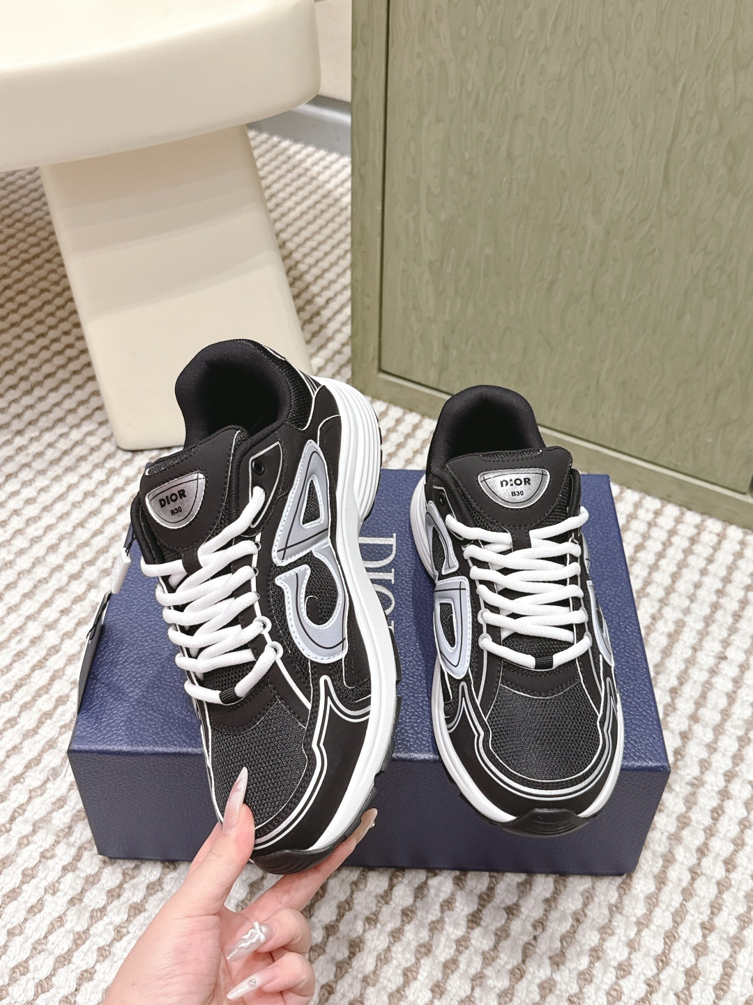 Black and white Dior unisex sneakers close-up with hand, front view