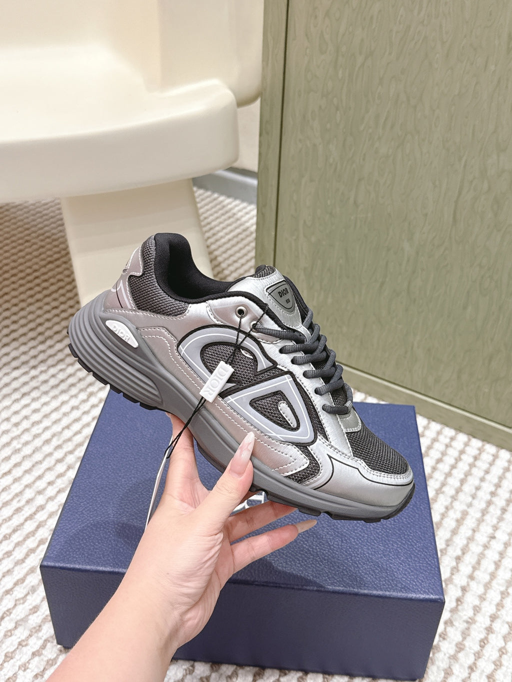 Grey and silver Dior sneakers, angled side view, with black tongue lining
