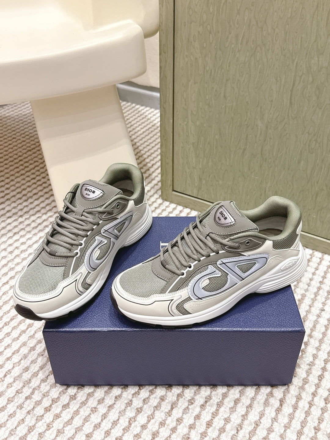 Grey lace-up sneakers with white midsoles and side logo detailing on both shoes