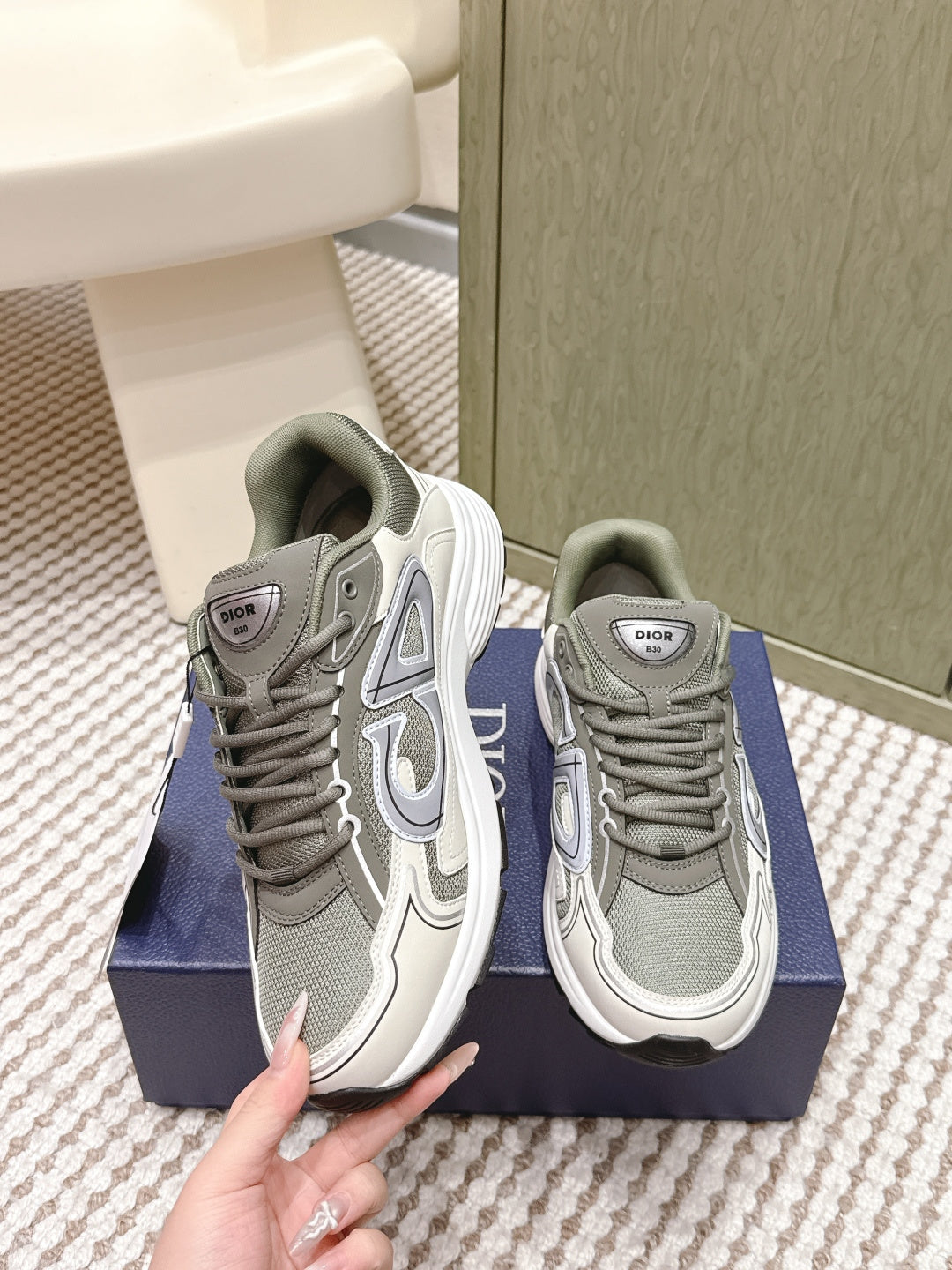 Pair of grey and white lace-up sneakers, showing front and side views on box
