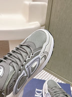Grey sneaker side view with white midsole, tread sole, and Dior branding on upper