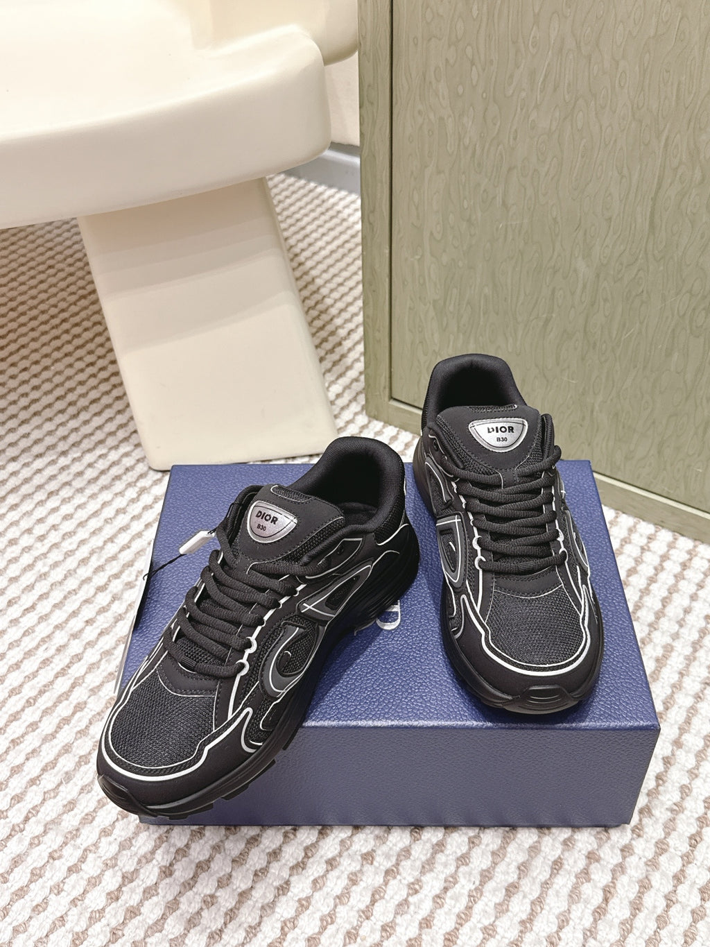 Black lace-up sneakers with white trim and Dior logo label at the tongue