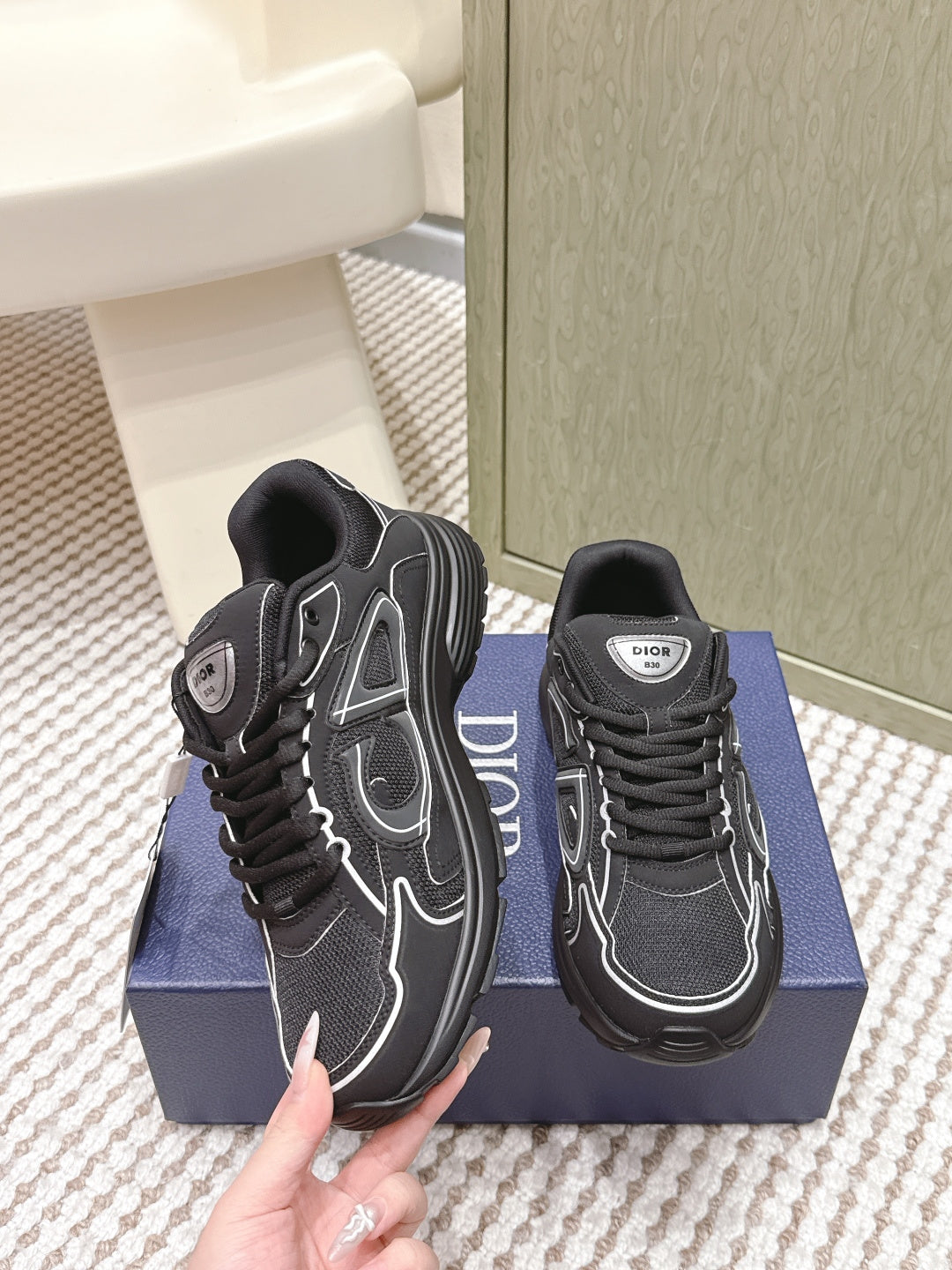 Black lace-up sneakers with white stitched overlays and Dior branding on tongue