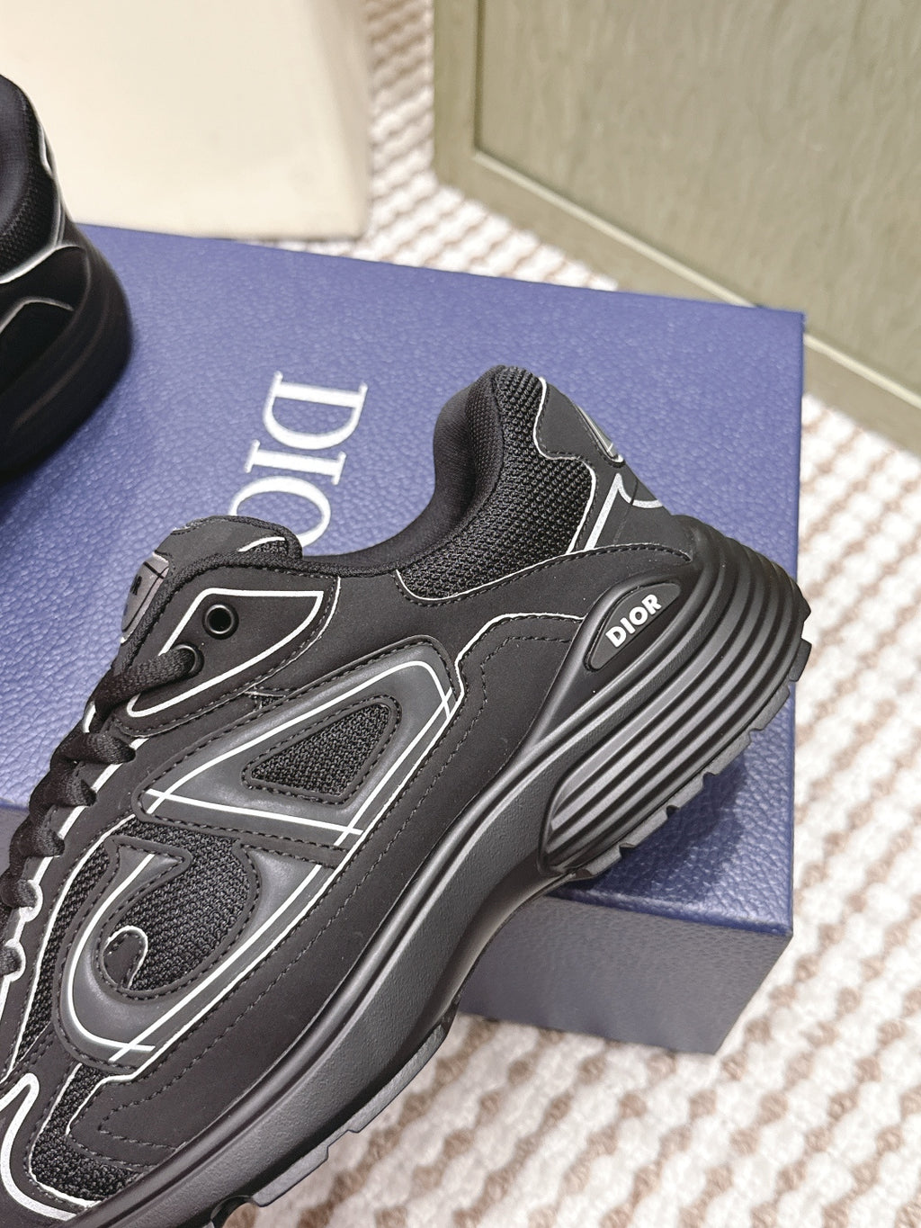 Black lace-up sneaker close-up with Dior logo, white trim, and textured panels